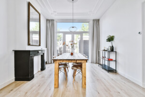 Wooden table with plant and chairs located in middle of light dining room in modern house